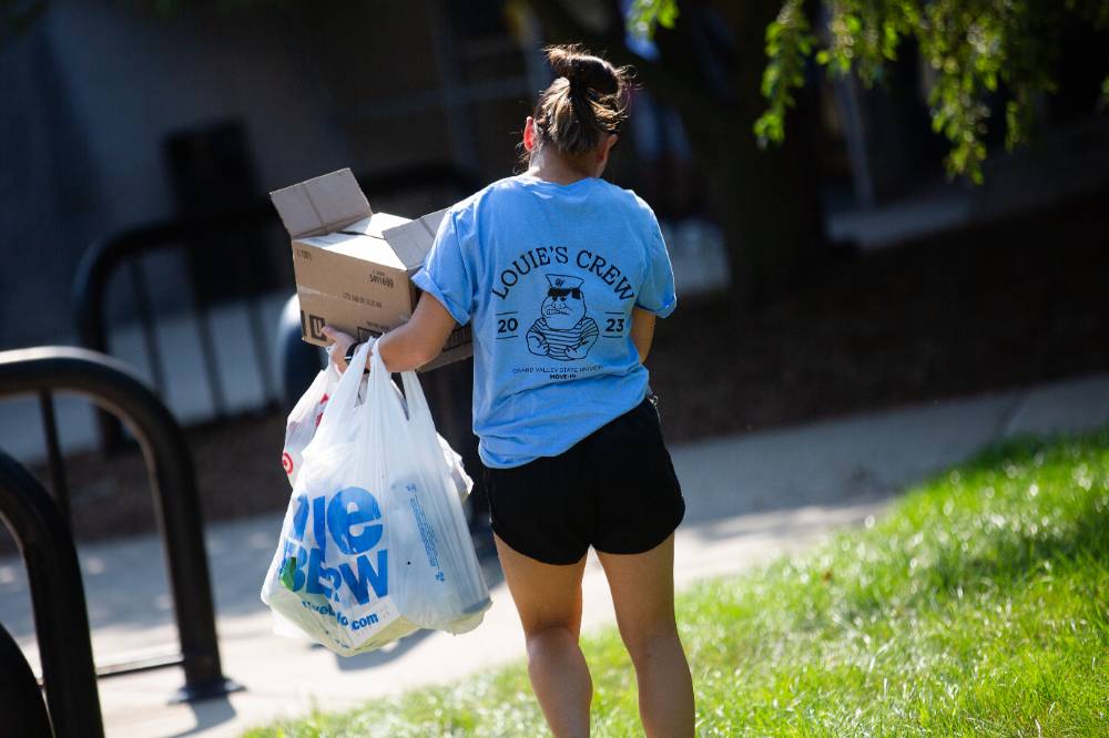 Alumna carrying a student's things to their dorm.